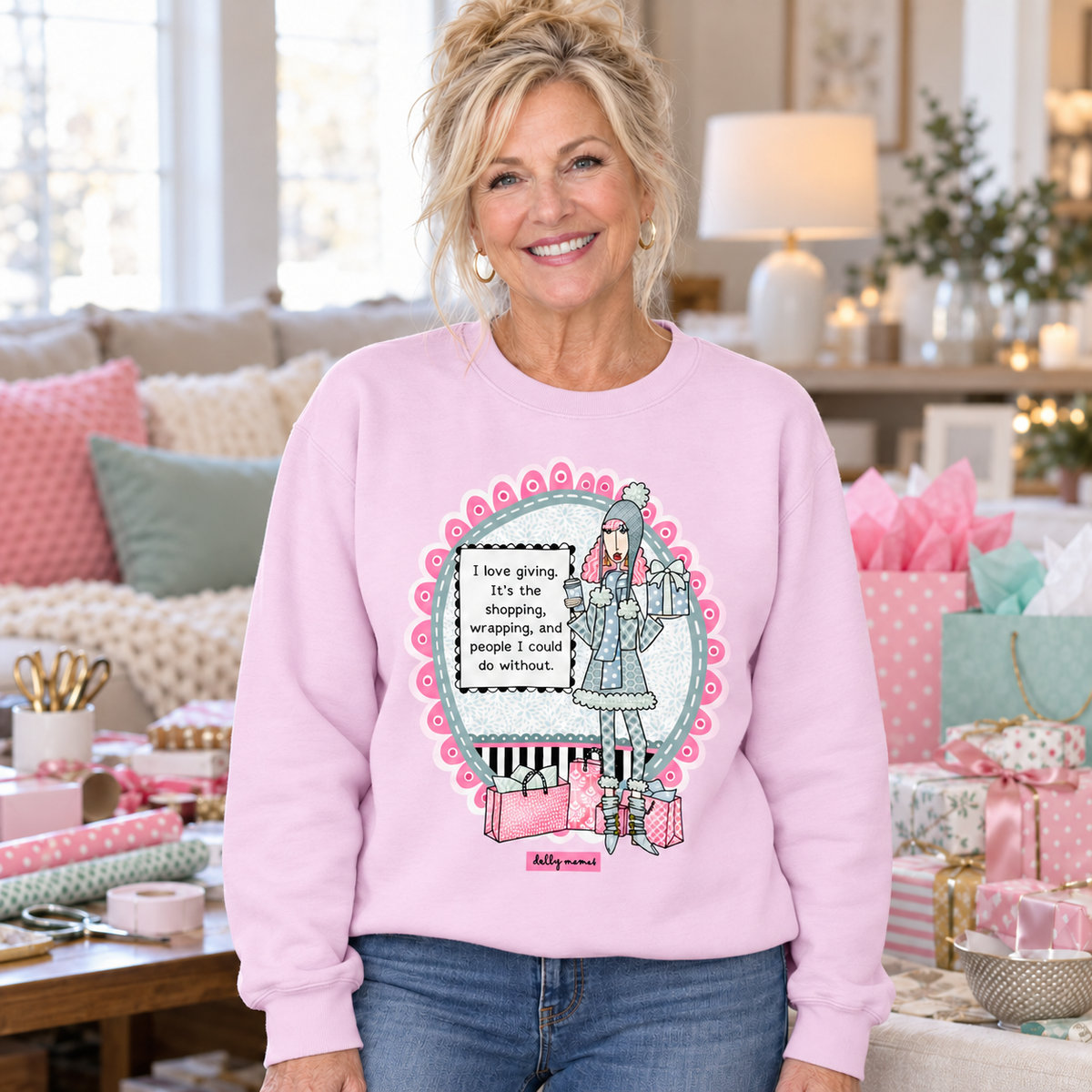 Woman wearing a lavender Dolly Mamas I Love Giving sweatshirt surrounded by pastel gift bags, wrapped presents, and wrapping supplies.