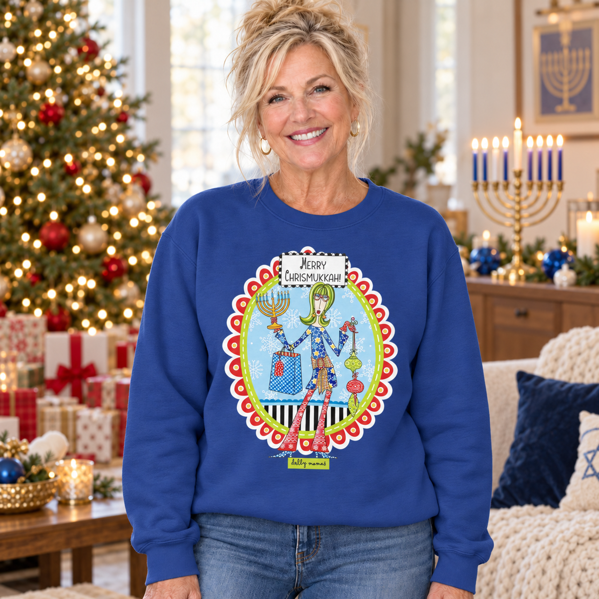 Woman wearing a royal blue Dolly Mamas Merry Chrismukkah sweatshirt beside a decorated Christmas tree and lit menorah.