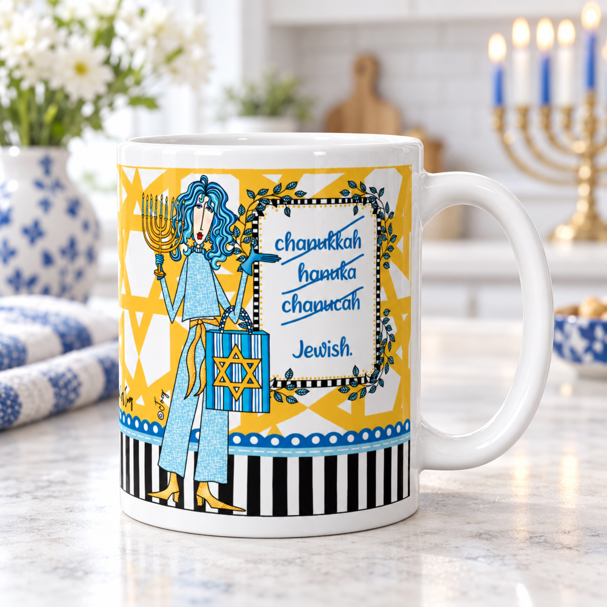 Dolly Mama Hanukkah mug with a blue-haired character and ‘Chanukkah… Hanuka… Chanucah… Jewish.’ saying, on a kitchen counter with a menorah in the background.