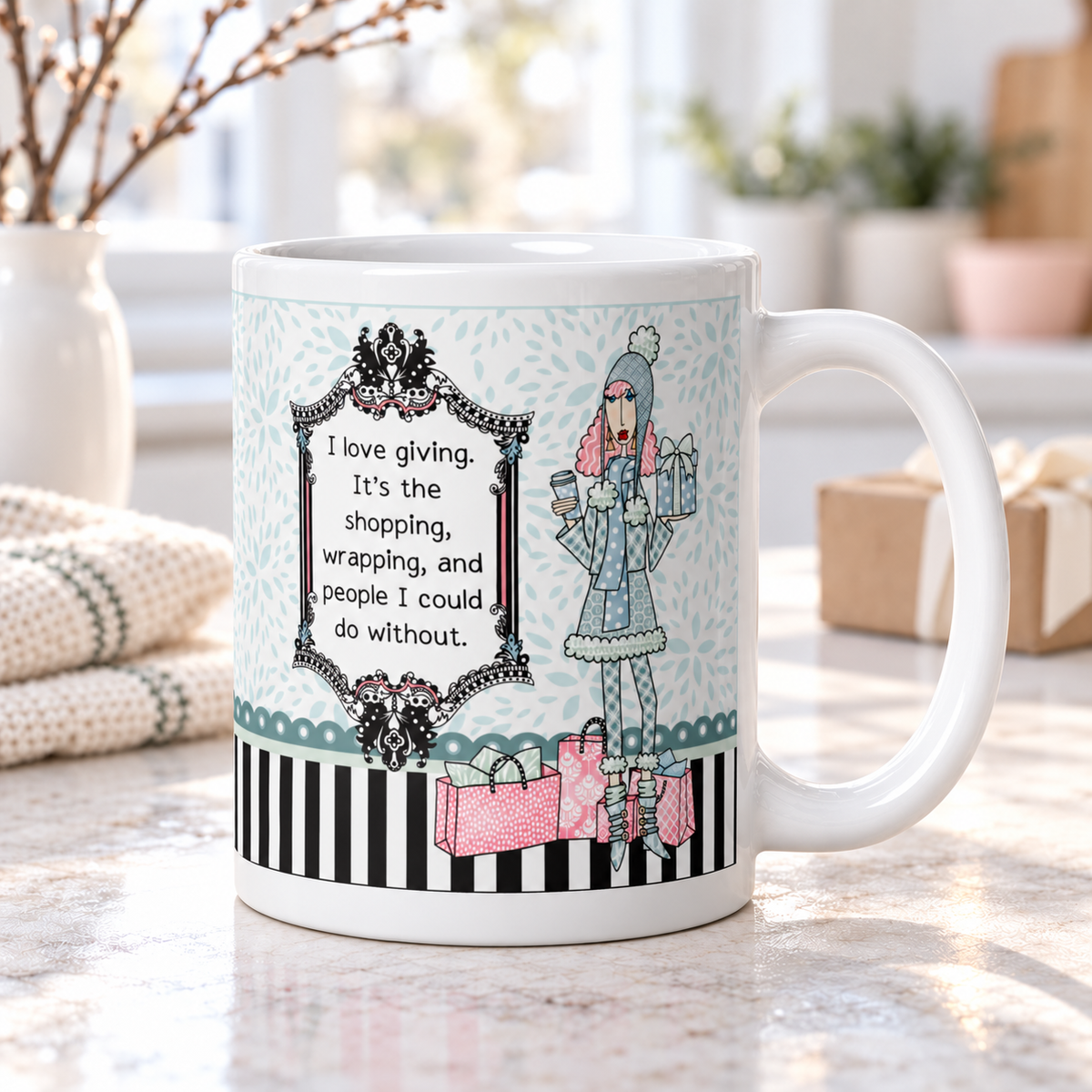 Dolly Mama “I love giving” mug on a bright kitchen counter, handle right, beside a knit blanket, vase of branches, and wrapped gift.