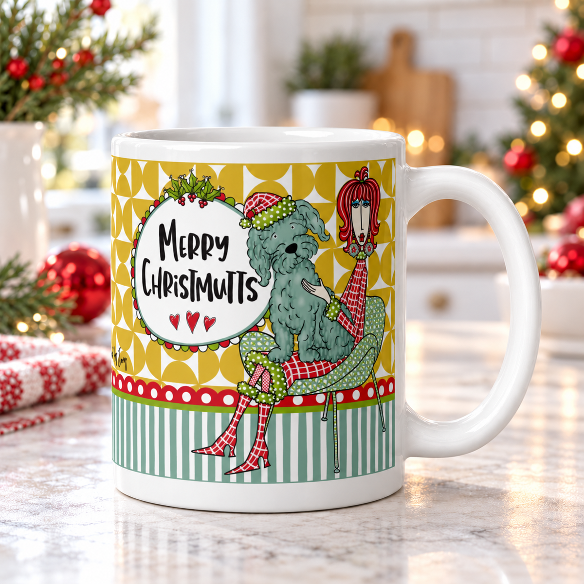 Dolly Mama “Merry Chrismutts” mug on a bright kitchen counter, handle right, with Christmas greenery and red ornaments.