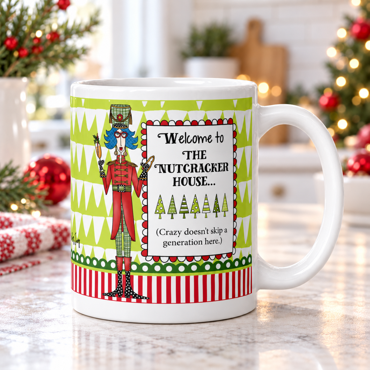 Dolly Mama “Welcome to the Nutcracker House” mug on a bright kitchen counter, handle right, with Christmas greenery and red ornaments.