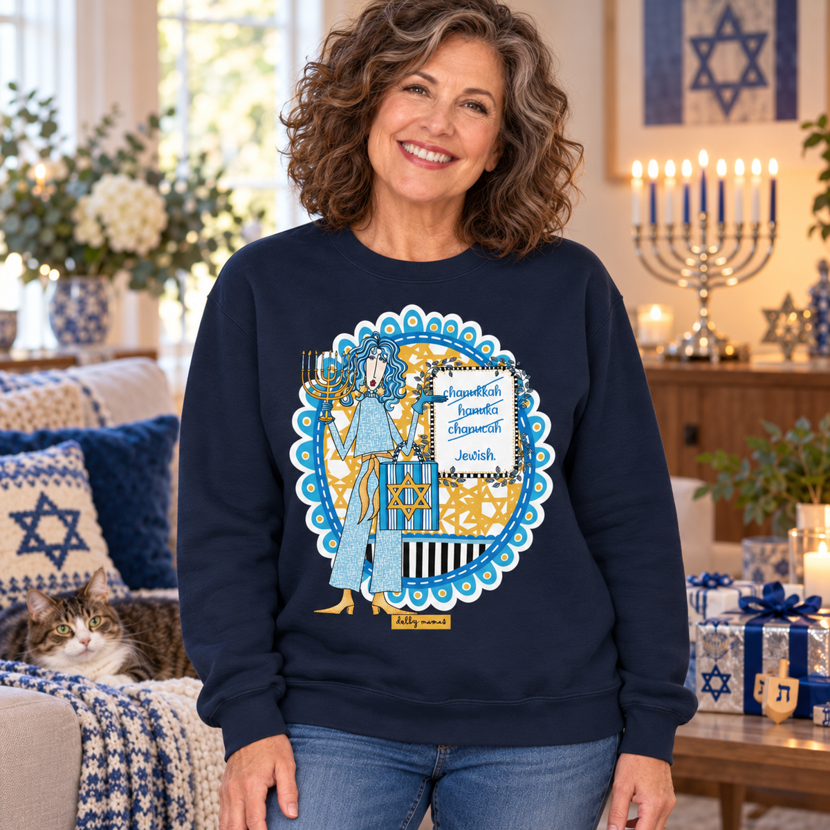 Woman wearing a navy Dolly Mamas Hanukkah sweatshirt in a festive living room with a lit menorah and a lounging cat.