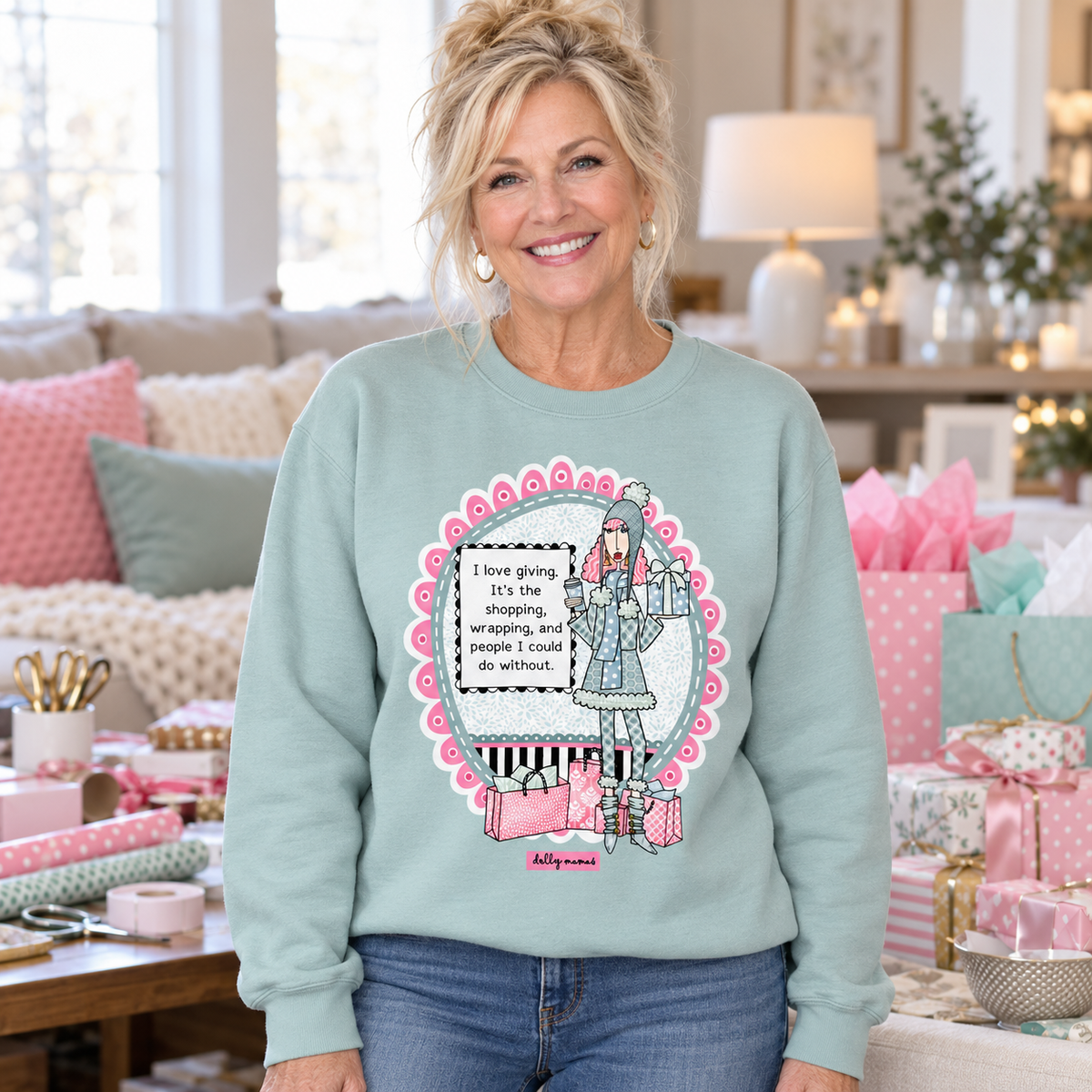 Woman wearing an agave Dolly Mamas I Love Giving sweatshirt surrounded by pastel gift bags, wrapped presents, and wrapping supplies.

