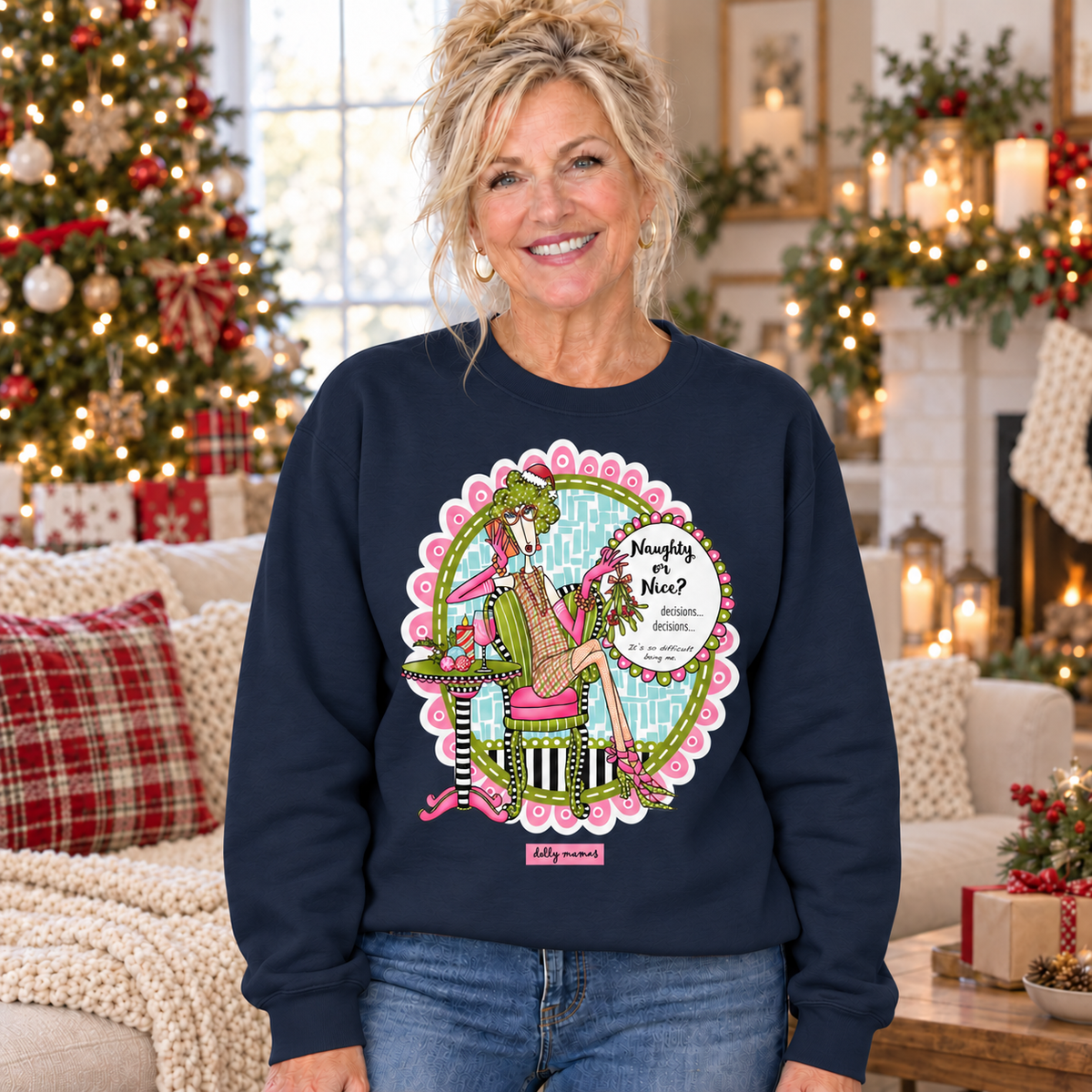Woman wearing a navy blue Dolly Mamas Naughty or Nice crewneck sweatshirt in a festive holiday setting.
